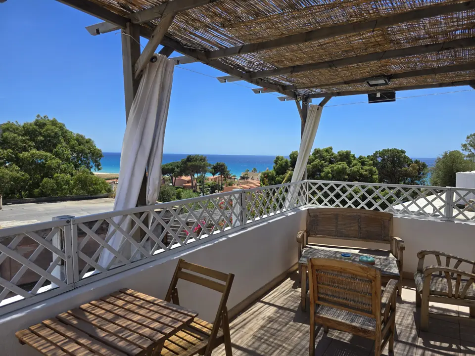 The terrace under the pergola, with the sea between the pines