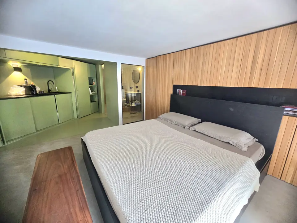 The bed, the wooden wall and the green kitchen behind